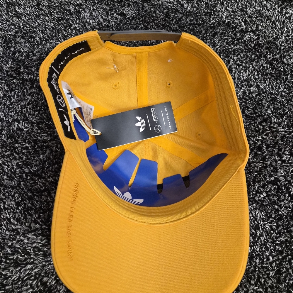 This cap is the Adidas x Bad Bunny x Mercedes-AMG F1 Racing Cap in gold.